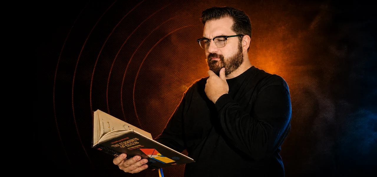 Glenn C. Hahn thoughtfully reading a book in dramatic amber and blue light